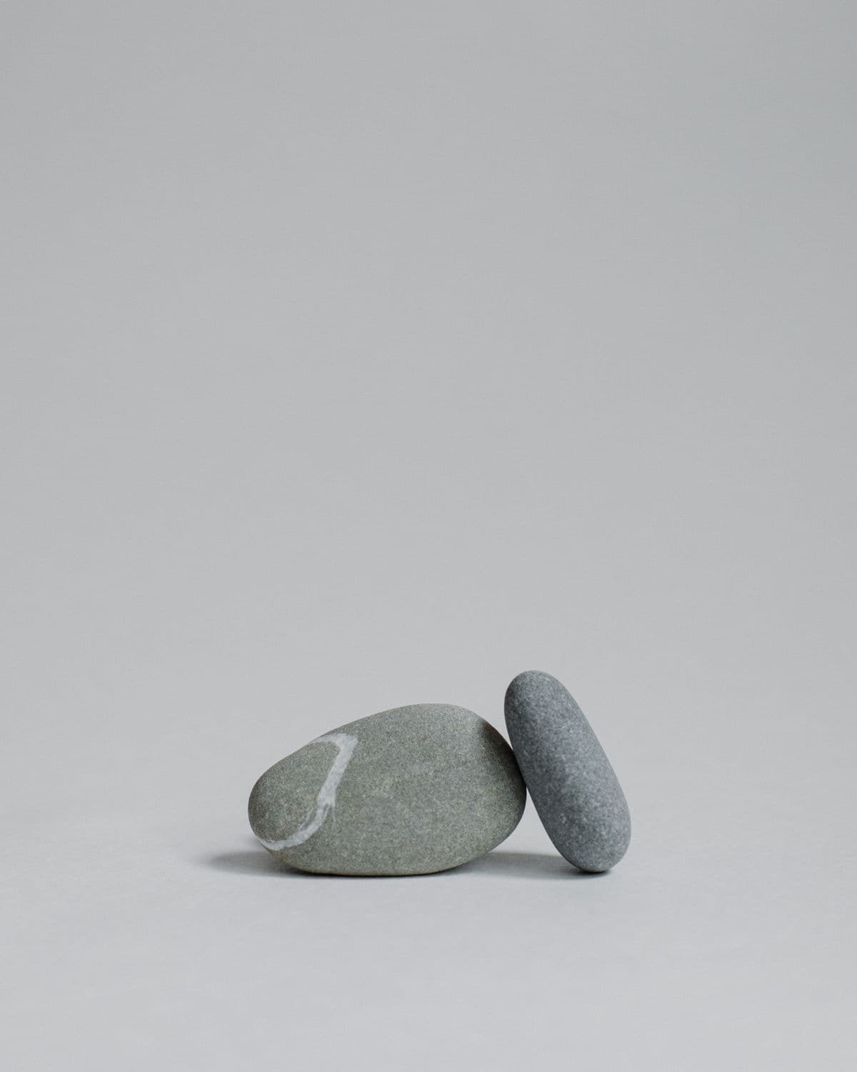 Two smooth stones arranged on a quiet neutral surface